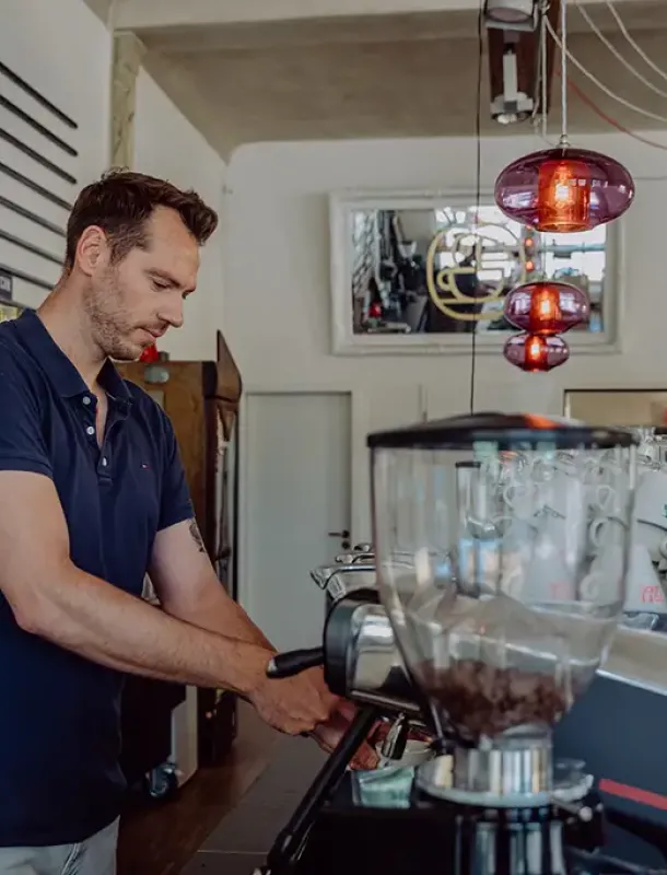 Mann an Siebträgermaschiene an den Tresen